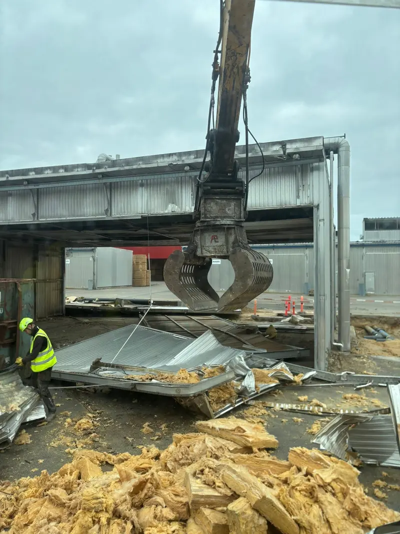 Gravemaskine med grab river industrihal ned